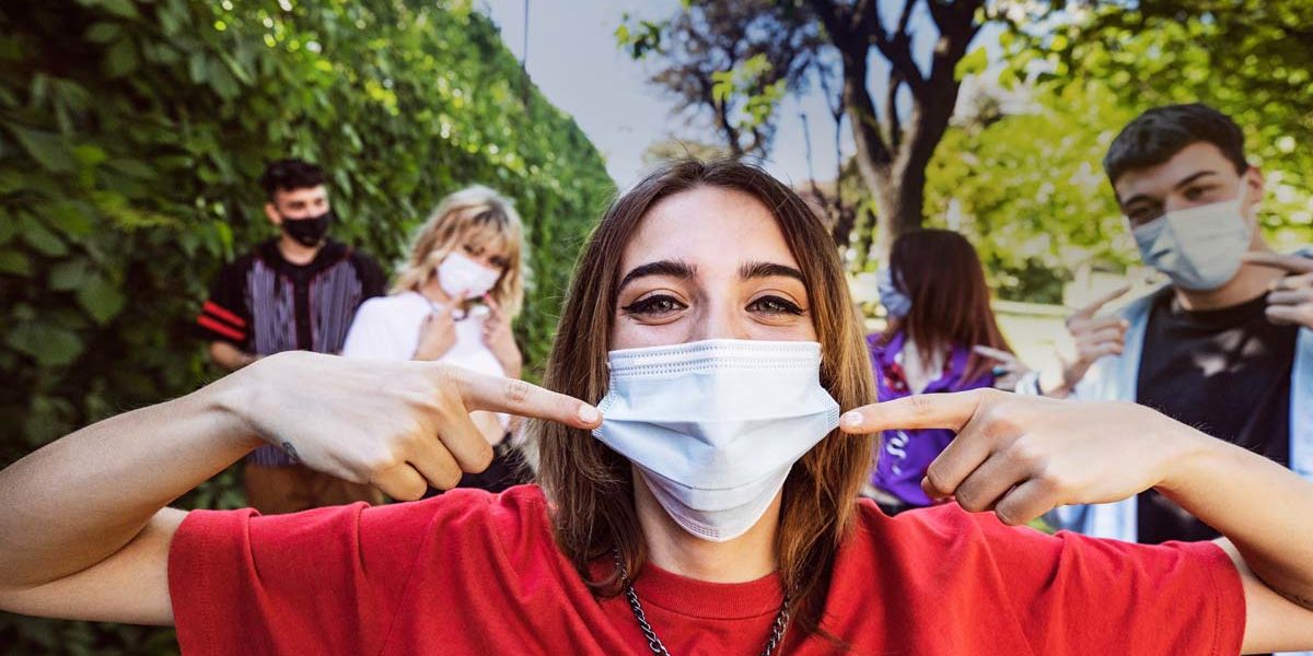 Group of teenagers posing showing their protective face masks during Covid-19 Coronavirus epidemic spread.